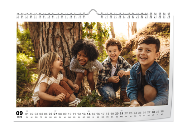 Fotokalender A4 Quer Digitaldruck matt zeigt fröhliche Kinder, die ausgelassen zwischen grünen Bäumen im Wald spielen.
